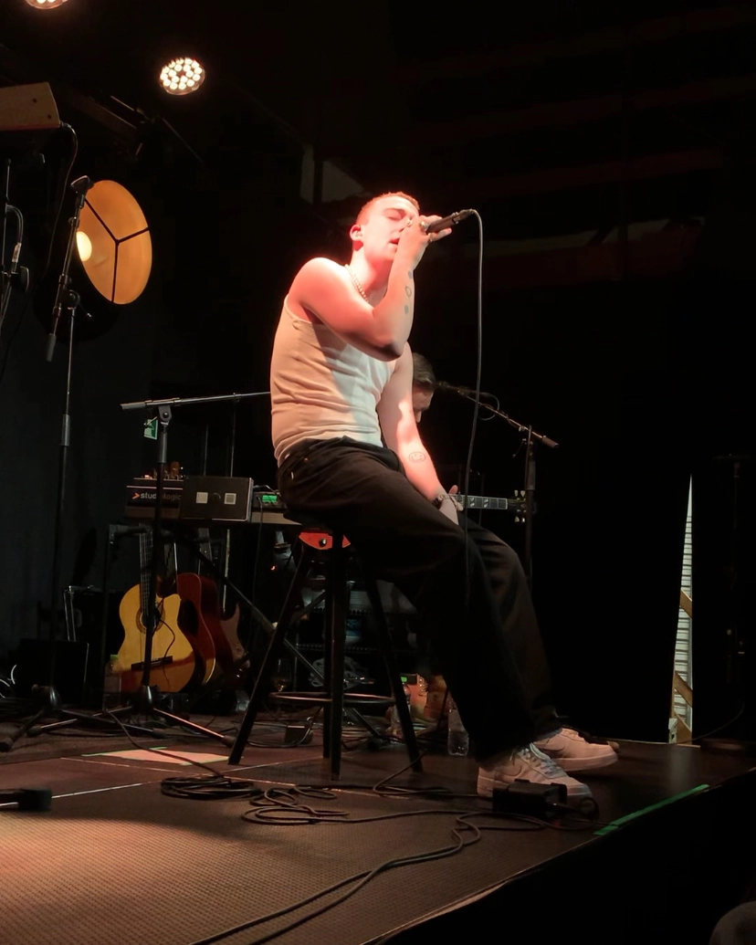 Billede af en countrysanger der sidder på scenen og spiller livekoncert